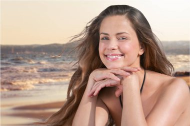 Güneş kremi süren güneş kremi kullanan kadın. Güzel, mutlu, tatlı bir kız, arka planda okyanusla yüzüne güneş kremi sürüyor. Güneş yanığı. Cilt Koruma