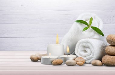 Açık ahşap arka planda havlular ve mumlarla spa kompozisyonu