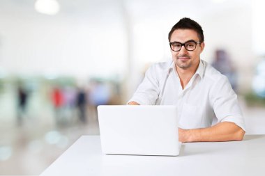 Kütüphanede dizüstü bilgisayarda çalışan mutlu adam.