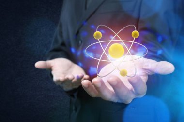 Adam eliyle vurgulama parlayan altın ve mavi atom modeli üzerinde koyu mavi arka plan bulanık. Bilim, kimya ve fizik kavramı. Kopya alanı görüntü çift pozlama tonda