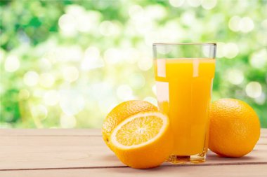 Bardakta taze portakal suyu ve bulanık arka planda ahşap masa.