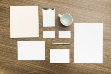 Ahşap zemin üzerinde boş kırtasiye seti / a4 kağıt, kartvizitler, antetli kağıtlar, kitapçık, not defteri ve bardak