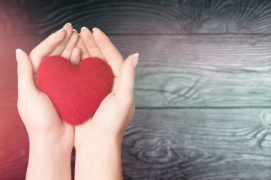 Yaşlı kadın ahşap arka planda kadın el desteği üzerinde aşk şekli egzersiz topu: Kalp hastalığı farkındalığı haftası: Amerikan kalp ayı: Kadınların kalp sağlığı konsepti için Ulusal Giyme Günü