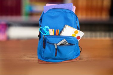 Ahşap masada mavi okul çantasını aç.