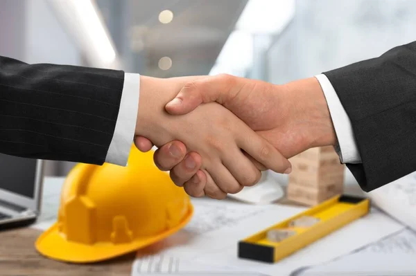 Close Businessmen Shaking Hands Table Blueprints Yellow Hardhat — Stock Fotó