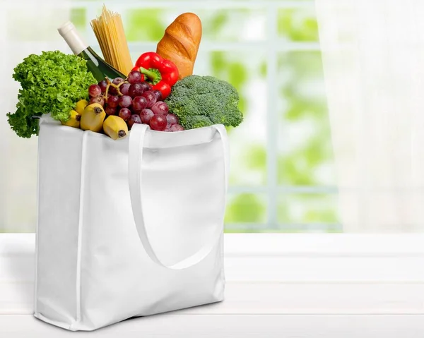 shopping bag with vegetables and fruits on table