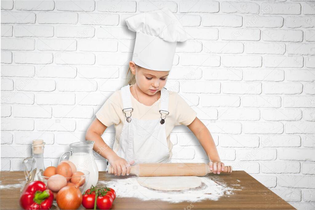 Happy little chef smeary with flour stretching the dough