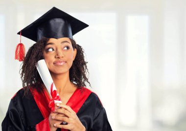 Siyahi mezuniyet şapkası ve elbisesi içinde üniversite diploması taşıyan gülümseyen değişim programı öğrencisi..
