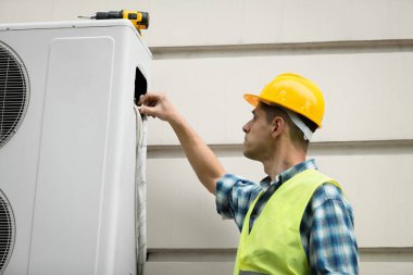 Teknisyen, havalandırma teknisyeni ve yeni klima montajının bir parçası. Teknisyen yeni klimayı kontrol ediyor.