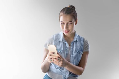 Arka planda duran akıllı telefonu kullanan genç ve güzel bir kadın..