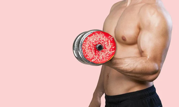 健康的なライフスタイルのための創造的なコンセプト ピンクの背景にドーナツとダンベル — ストック写真