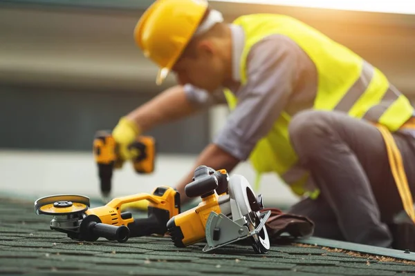 戴防护手套的屋顶工人 在正在施工的住宅楼新屋顶上使用或建造电动工具 — 图库照片