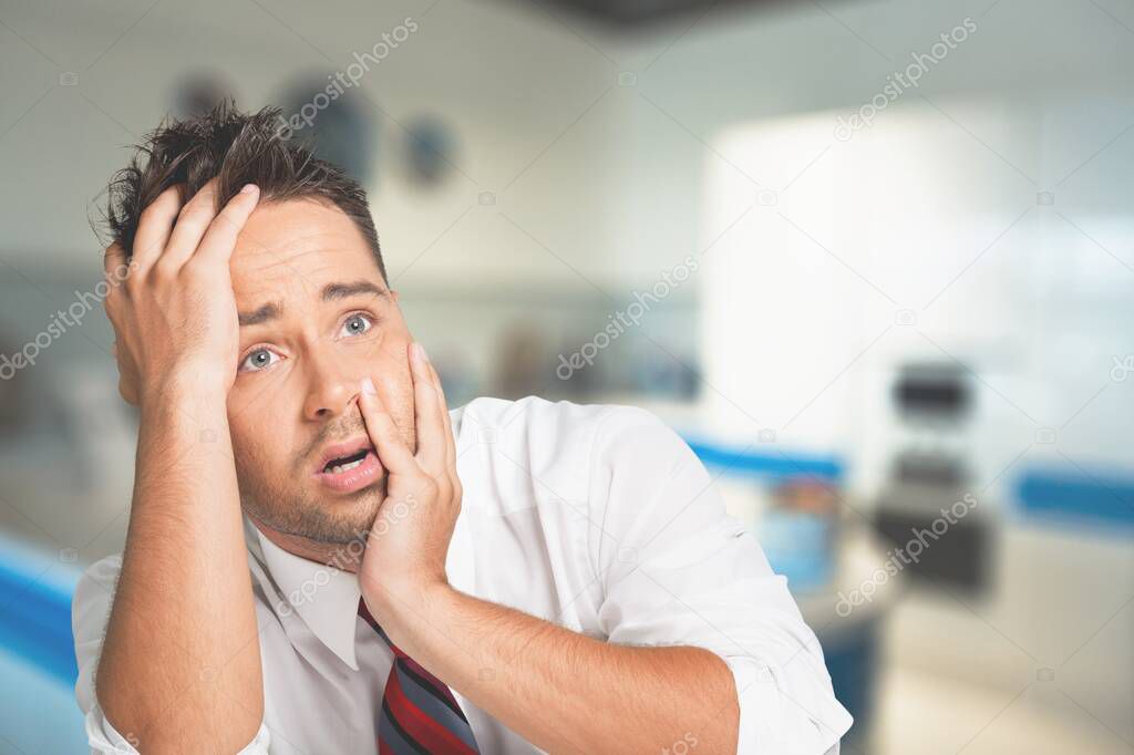The frustrated middle-aged man sitting in living room, touching his head, having troubles.