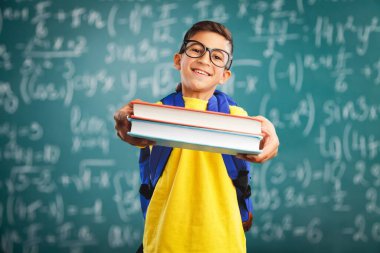 Öğrenci üniforması içinde elinde kitap, okul eğitimi tutan mutlu, sevimli çocuk.