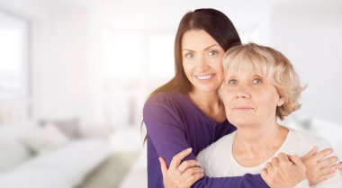 Mutlu anne ve kız gülümsüyor. Arka planda dikilip sarılıyorlar..