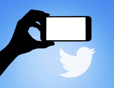 Twitter logosu önünde elinde cep telefonu olan bir sosyal ağ sayfası.