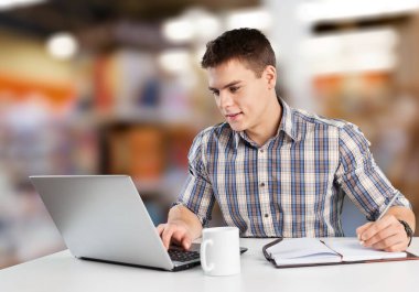 Genç işadamı konuşuyor, tele-çalışıyor, sanal toplantı yapıyor, dizüstü bilgisayarla çalışıyor..