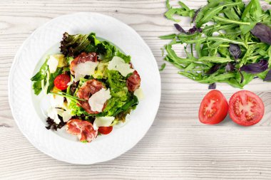 Mutfak masasındaki beyaz tabakta yeşil salata. Sağlıklı yiyecekler, temiz yeme konsepti.