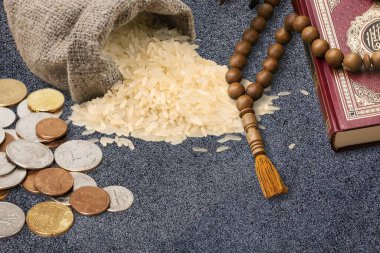 Raw rice in the sack with coins, rosary and Koran. clipart