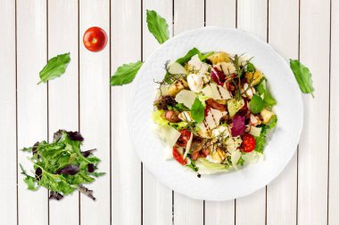 Mutfak masasındaki beyaz tabakta yeşil salata. Sağlıklı yiyecekler, temiz yeme konsepti.