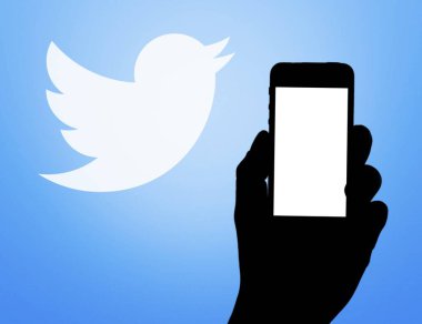 Twitter logosu önünde elinde cep telefonu olan bir sosyal ağ sayfası.