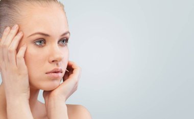 Mutlu genç kadın mükemmel tenine dokunuyor. Yüz tanıtım ürünlerinin güzel portresi.