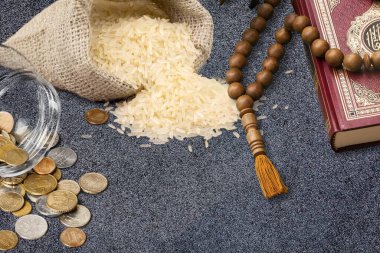 Raw rice in the sack with coins, rosary and Koran. clipart
