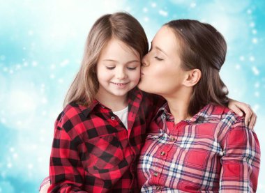 Mutlu bir kadın tatlı bir çocukla eğlenir, yanağından öper.