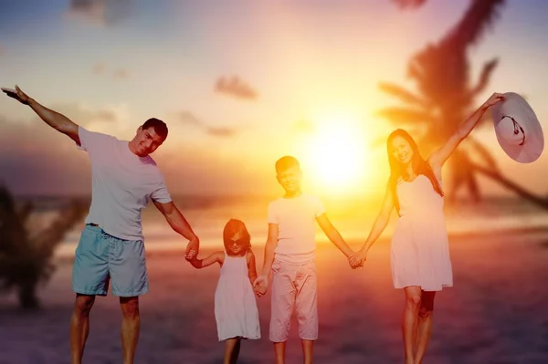 日落时年轻快乐的一家人在海滩上散步 — 图库照片