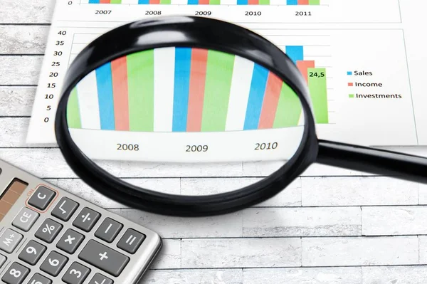 Magnifying glass on charts graphs paper. Financial, Banking concept.