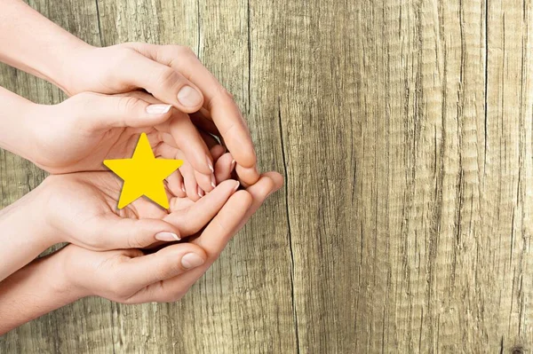 Hands of a kid giving a Star Rating to mother. Mother and kid child hand holding star.