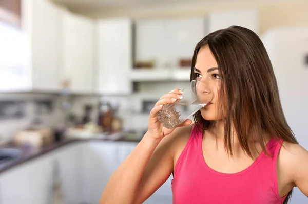 健康的な液体 美しいブルネットの女性は台所のガラスから水を飲む — ストック写真
