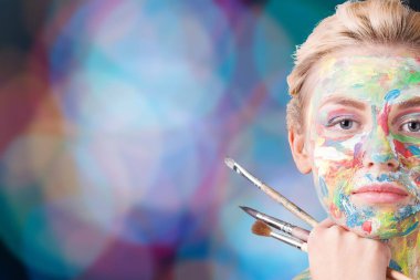 Genç güzel kadın ile boyalı yüz ve Boya fırçaları