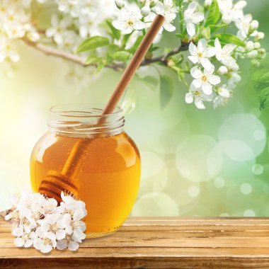 Tatlı bal kavanozu bahar çiçekleri etrafını sarmış.