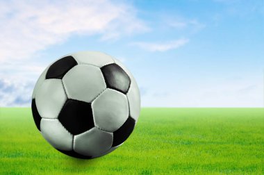 Klasik futbol topu stadyumdaki yeşil çimlerde yatıyor.