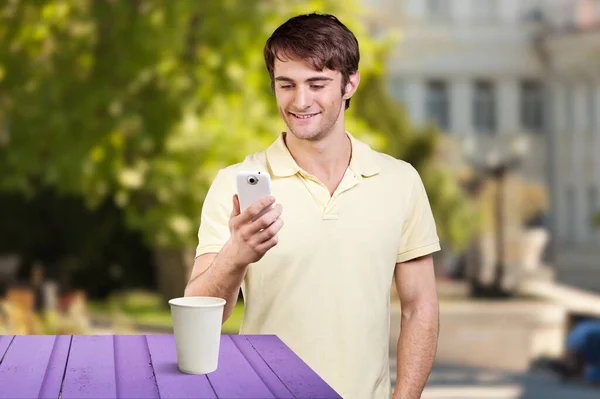 若い幸せな男屋外で彼の携帯電話を使用して — ストック写真