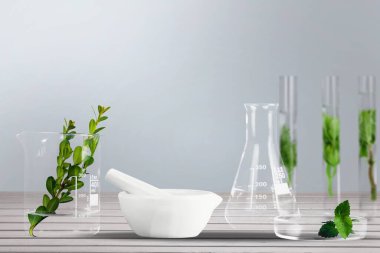 Yeşil sıvı ve beyaz zemin üzerinde taze bitkiler bulunan cam bezler.