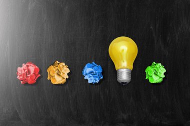 Arkaplanda ampul olan renkli buruşuk bir kağıt top..