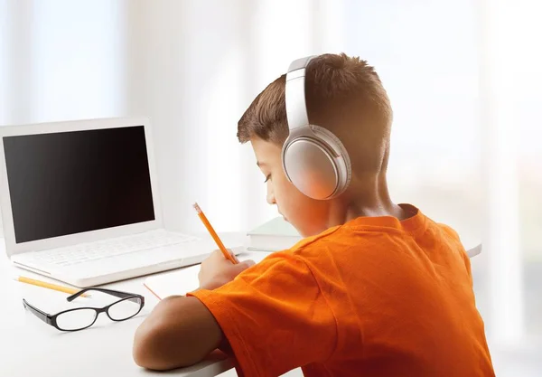 Niño Con Portátil Auriculares Haciendo Tarea Hogar —  Fotos de Stock