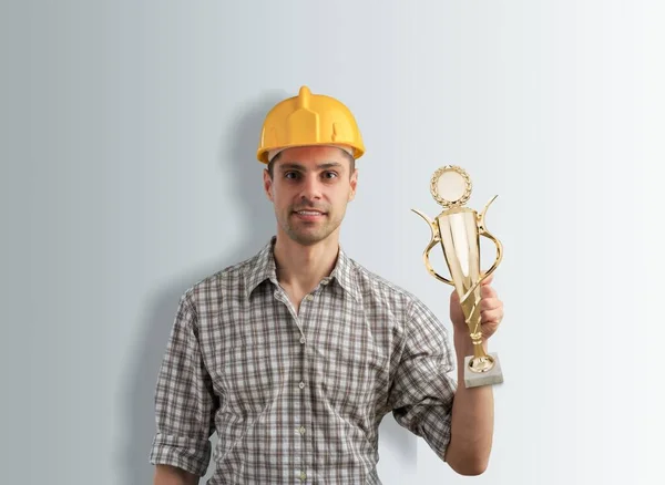 戴着硬礼帽的建筑商手里拿着金杯 年度最佳工作者概念 — 图库照片