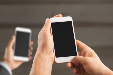 İnsan ellerinde boş ekranları olan iki modern akıllı telefon.