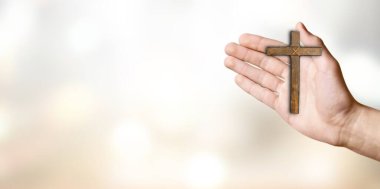 Beyaz arka planda ahşap bir haç tutan el.