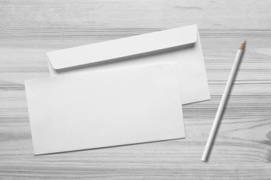Ahşap zemin üzerinde kalem ve kalem olan boş beyaz zarflar