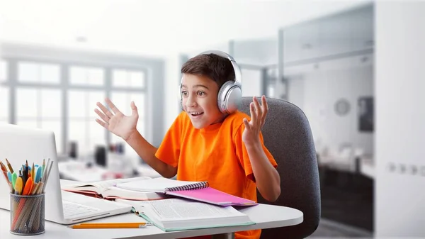带着笔记本电脑和耳机的男孩在家里做作业 — 图库照片