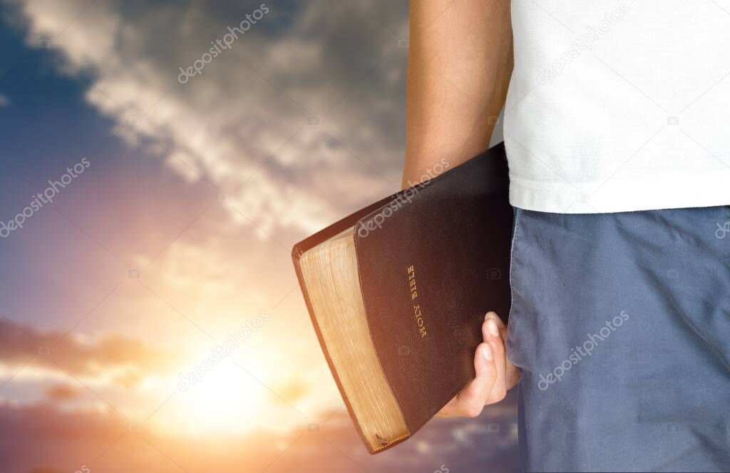 man holding bible on a blue sky background