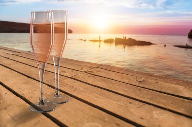 Denizin arka planında bir bardak köpüklü şampanya