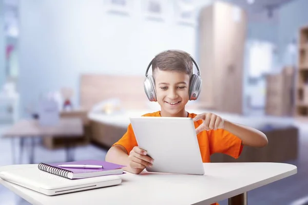 带着笔记本电脑和耳机的男孩在家里做作业 — 图库照片