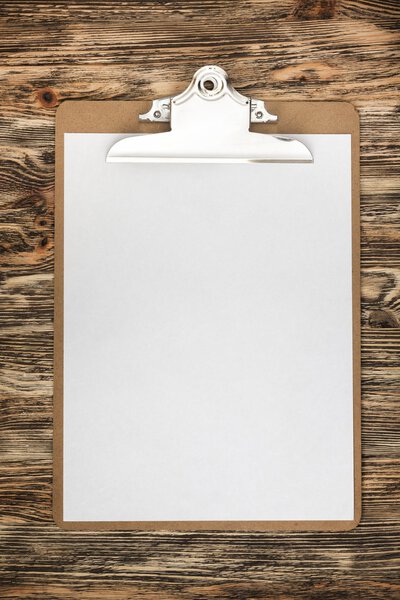 Notepad. Clipboard with a blank sheet of paper on wooden table