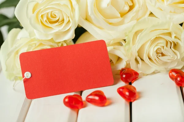 Dag. Donkere rode rozen met twee hartjes en tag op houten tafel — Stockfoto