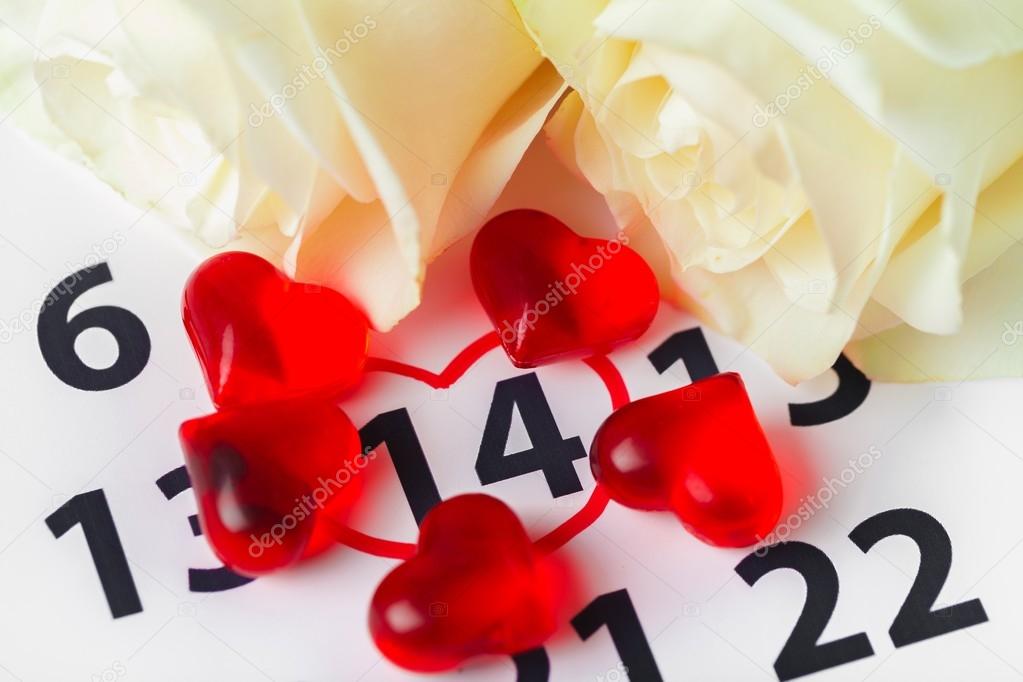 Calendar. Red roses lay on the calendar with the date of February 14 Valentines day